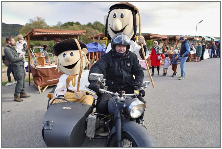 Návštevníci Mitrovania na Salaši pod Maginhradom vo Veľkých Teriakovciach medzi remeselnými stánkami, v postranom vozíku motorky sedia bábky valachov